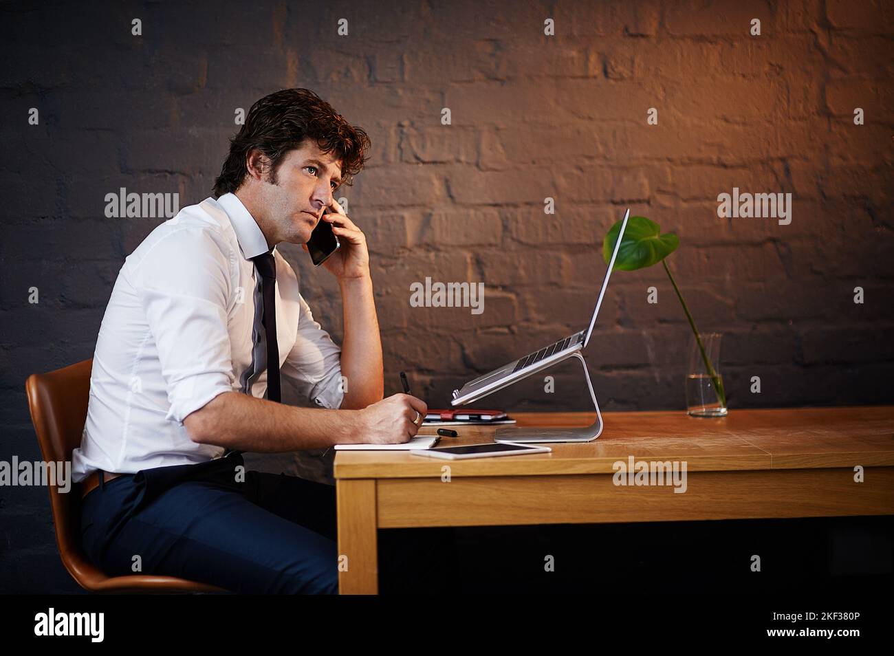HES a eu un client important sur la ligne. Un homme d'affaires parlant au téléphone tout en travaillant tard au bureau. Banque D'Images