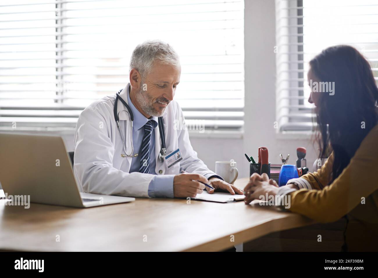 S'engage à la santé de ses patients. Un médecin ayant une consultation avec un patient dans son bureau. Banque D'Images