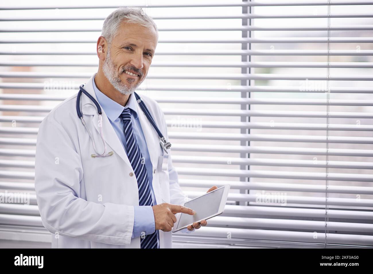 Utiliser le technicien à son avantage dans son cabinet médical. Portrait d'un médecin de sexe masculin mature utilisant une tablette numérique. Banque D'Images