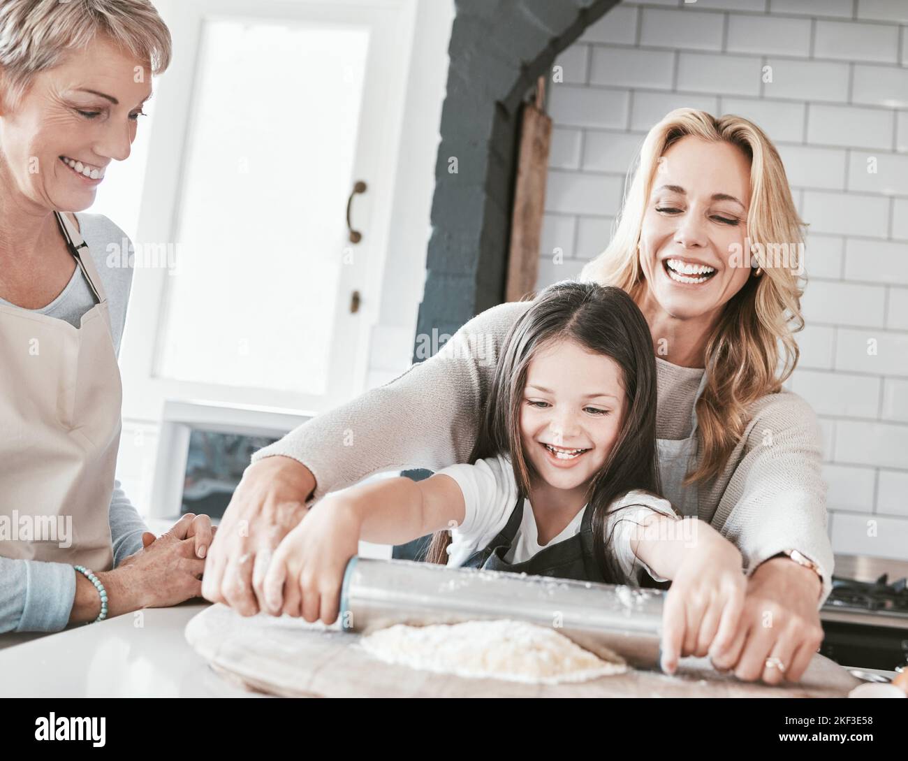 .La cuisine et la cuisson de la mère, de la grand-mère et de l'enfant avec une broche à roulettes pour la pâtisserie, la tarte ou la pizza dans la cuisine familiale. Femme, senior et fille aidant Banque D'Images