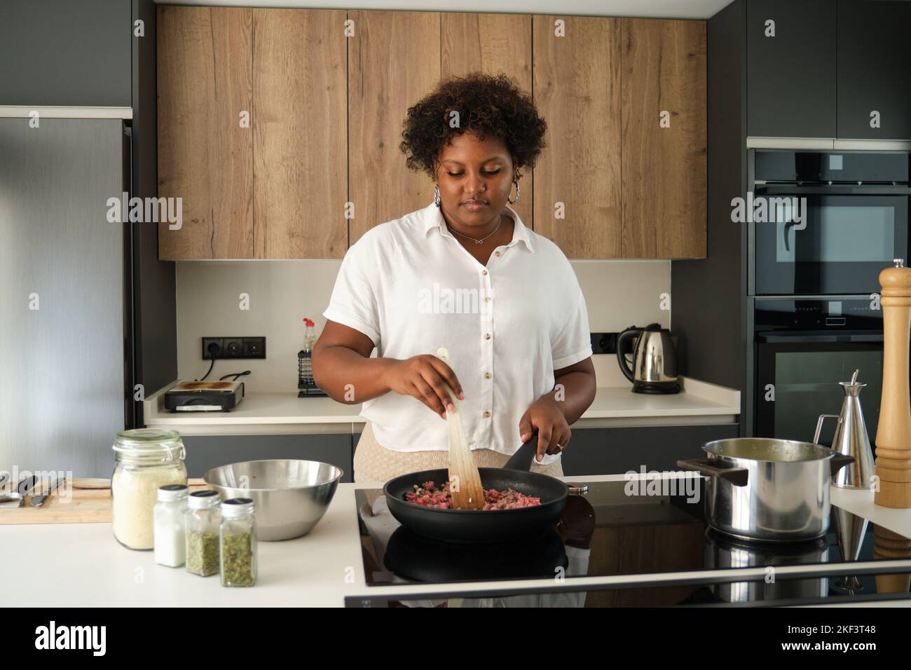 Jeune femme cubaine cuisant du bœuf haché et de l'ail dans une casserole. Banque D'Images