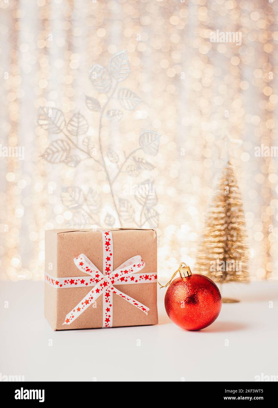 Boîte cadeau avec boule rouge et petit arbre de noël Banque D'Images
