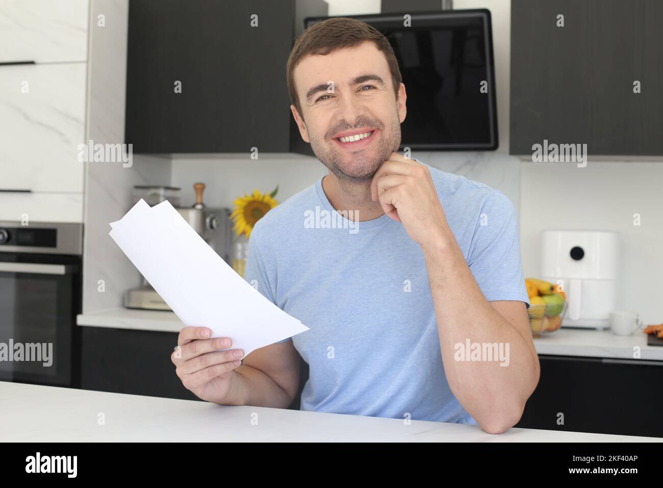 Homme satisfait regardant quelques documents dans la cuisine Banque D'Images