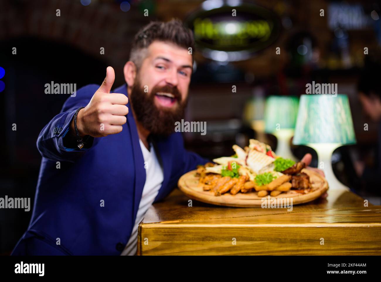 En-cas à haute teneur en calories. Détendez-vous après une dure journée. Plats délicieux. Costume d'homme d'affaires habillé assis au restaurant. L'homme a reçu un repas avec des bâtonnets de pommes de terre frits Banque D'Images