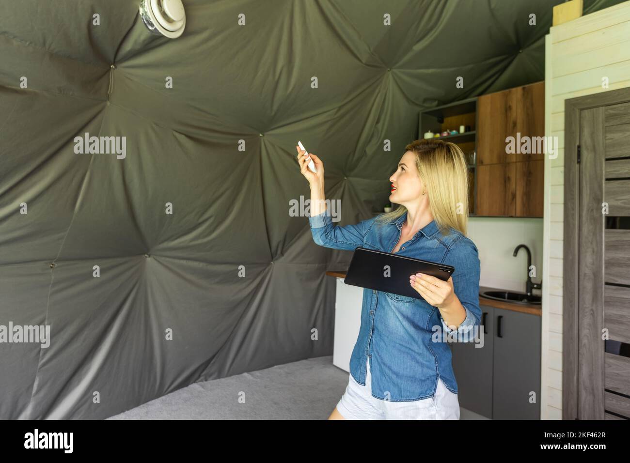 femme avec une tablette qui active le système de ventilation comme récupérateur pour la qualité de l'air frais à l'intérieur, maison intelligente Banque D'Images