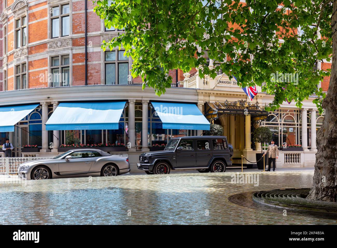 L'impressionnant Connaught Hotel de Mayfair est l'un des meilleurs hôtels de luxe de londres.deux voitures de luxe sont garées, un concierge se tient à l'entrée. Banque D'Images