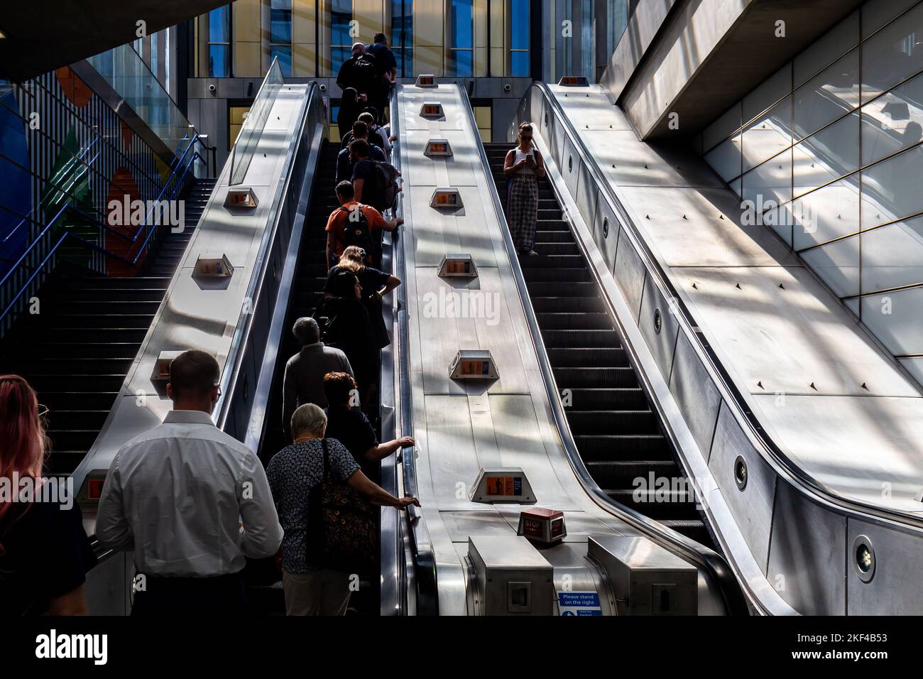 Escaliers roulants sur le métro Tottenham court avec éclairage latéral spectaculaire transportant plusieurs passagers en début de matinée pour travailler. Banque D'Images