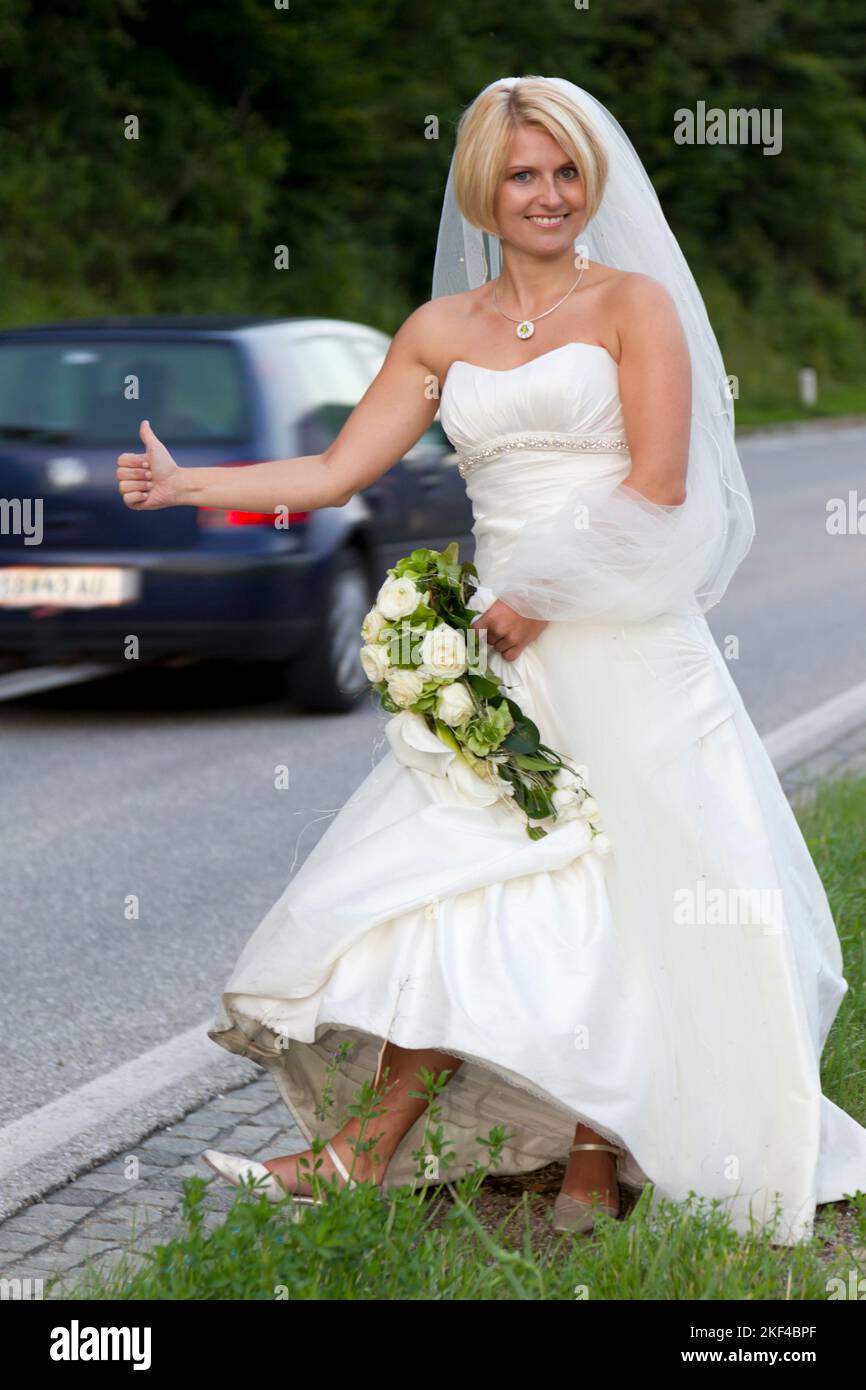 Eine fröhliche Braut steht an der Strasse per Anhalter, Hochzeitsspass, Hochzeitspass, Tradition, Entführung der Braut, Banque D'Images