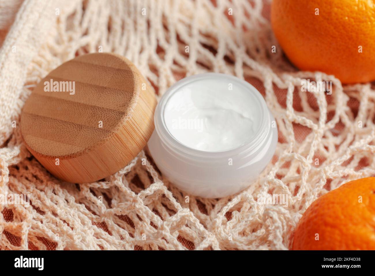 Pot de crème de bambou sur le fond d'un sac en maille de coton et de mandarines. Produit de beauté biologique. Concept zéro déchet. Banque D'Images