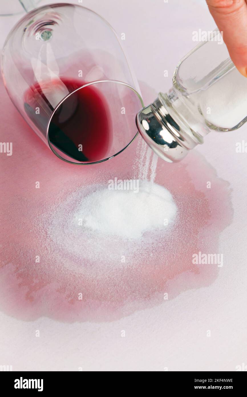 Ein umgefallènes Glas mit Rotwein verschmutzt einen Teppichboden. Reinigen mit Salz, Rotweinflecke, Banque D'Images