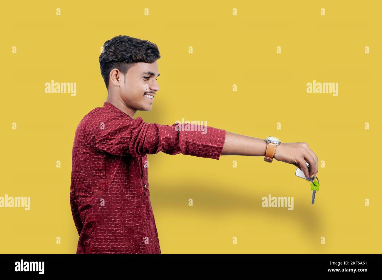 Homme tenant ou donnant la clé de la maison sur le festival indien DIWALI isolé sur fond jaune Banque D'Images