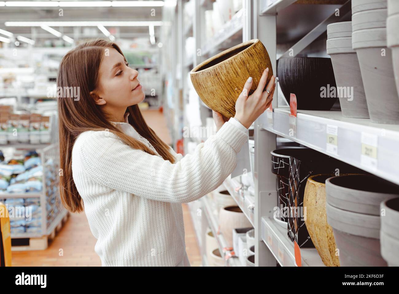 Une femme choisit un pot pour les plantes à la maison dans un magasin de serre, un magasin de quincaillerie, des achats pour la maison et des articles d'intérieur. Banque D'Images