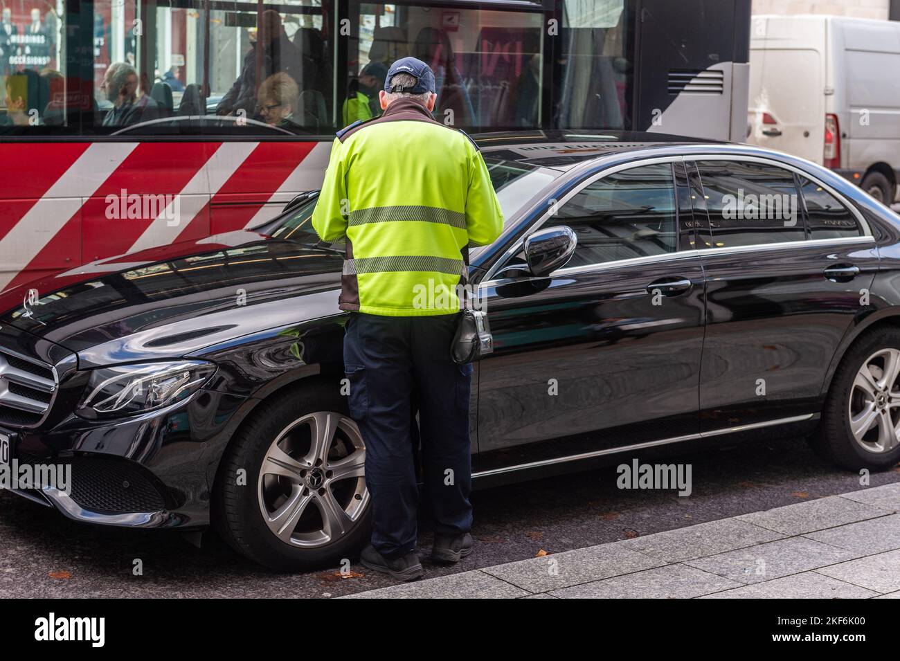 Garde-trafic émettant un billet de stationnement pour une voiture garée illégalement à Cork, en Irlande. Banque D'Images