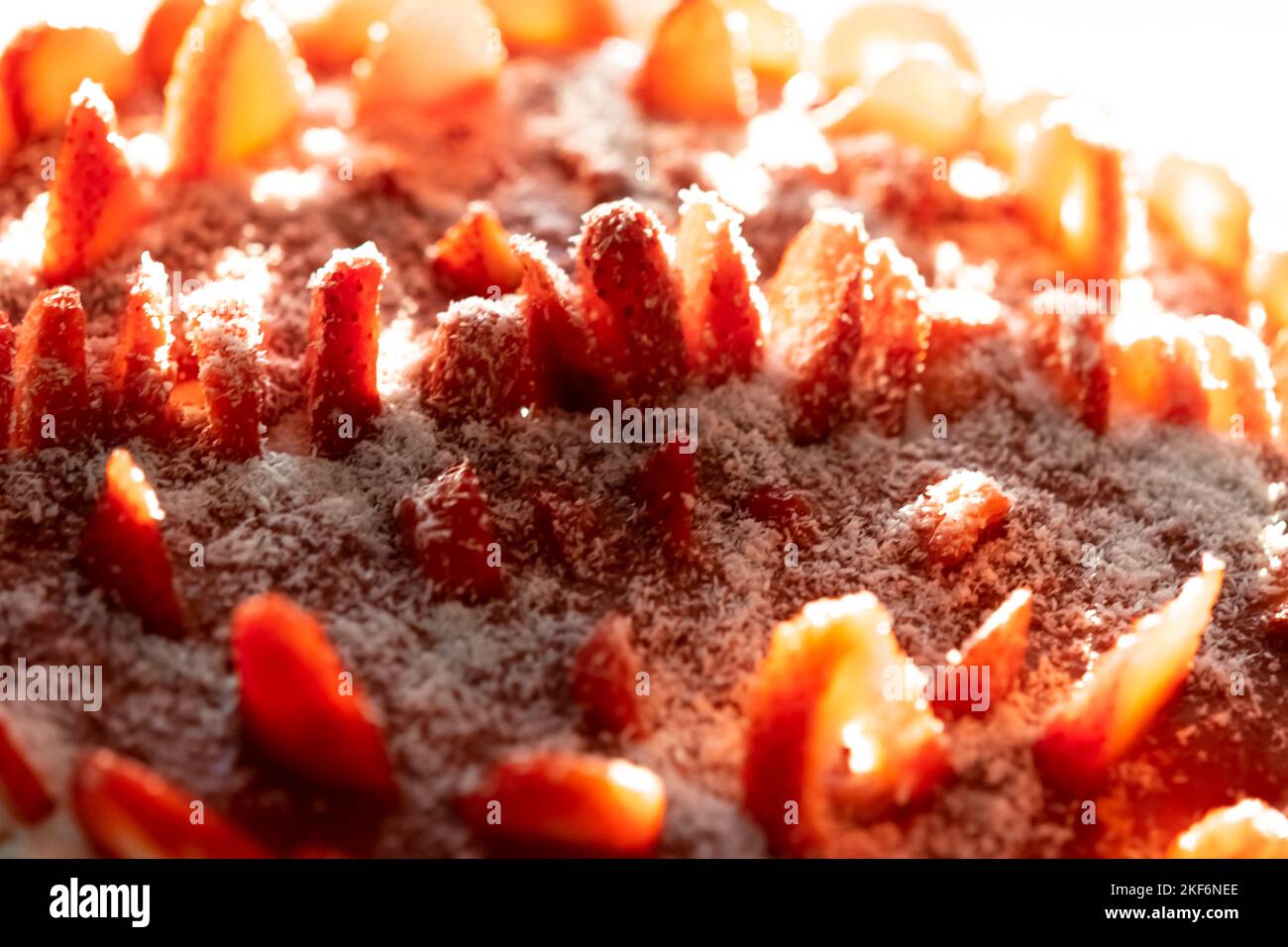 tarte aux fraises noix de coco arrosée vue latérale macro photographie dans une plaque circulaire sous la lumière naturelle du jour. Faible profondeur de champ avec mise au point sélective. Banque D'Images