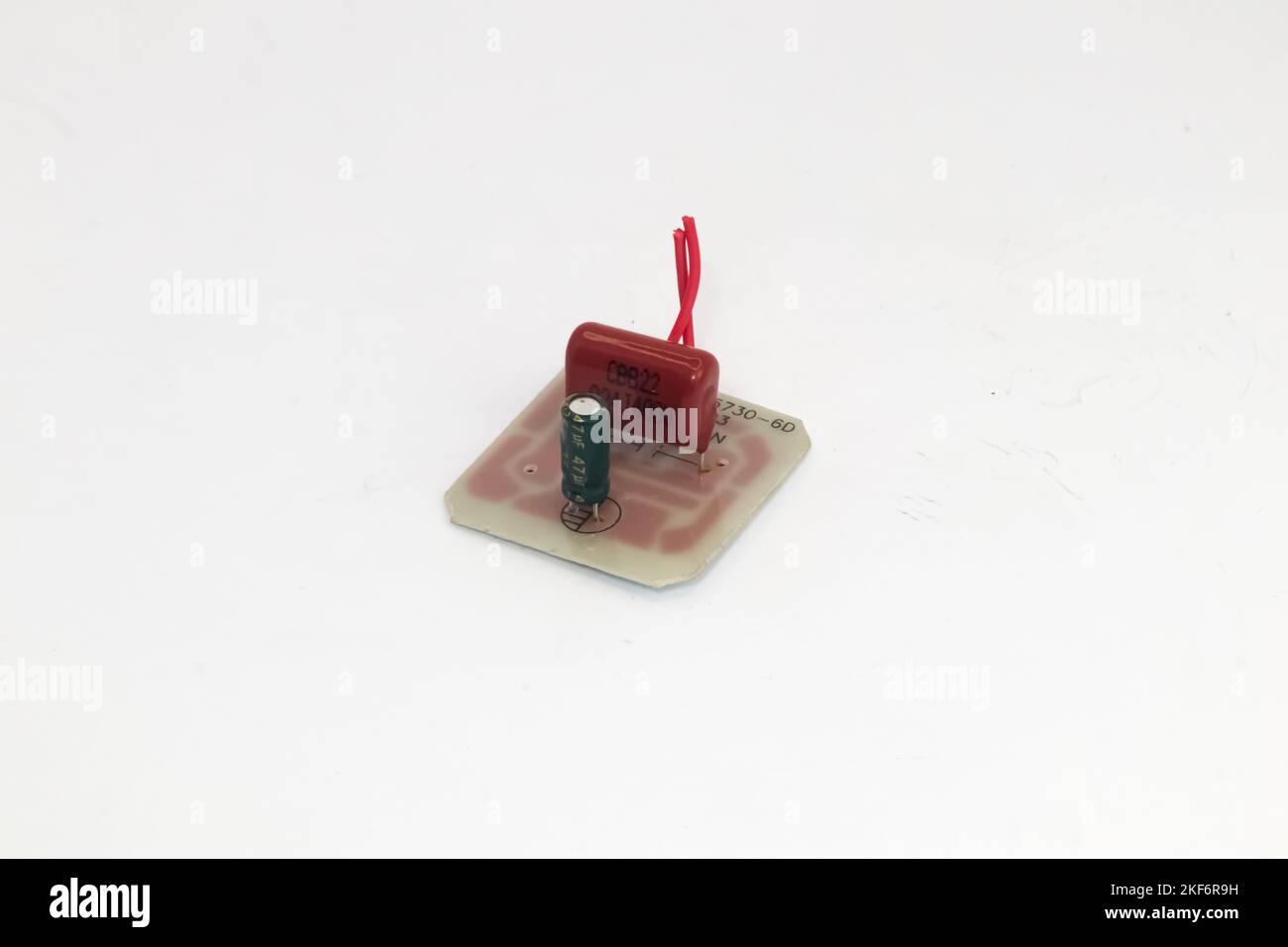 Un circuit imprimé avec deux condensateurs avec fils rouges sur fond blanc. Banque D'Images