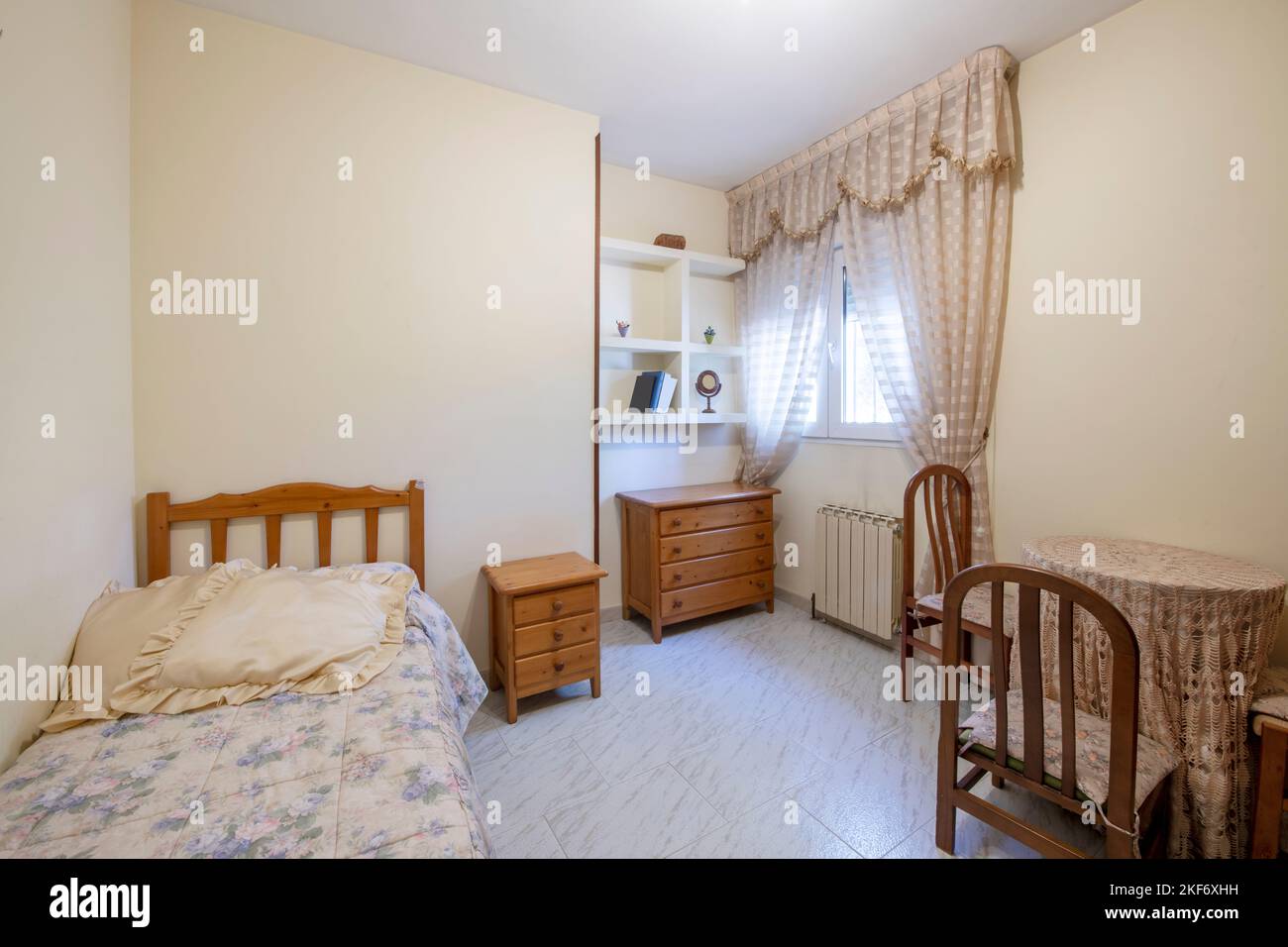 cette chambre comprend un petit lit double avec des meubles en pin de couleur miel et une table de chevet avec des chaises assorties Banque D'Images