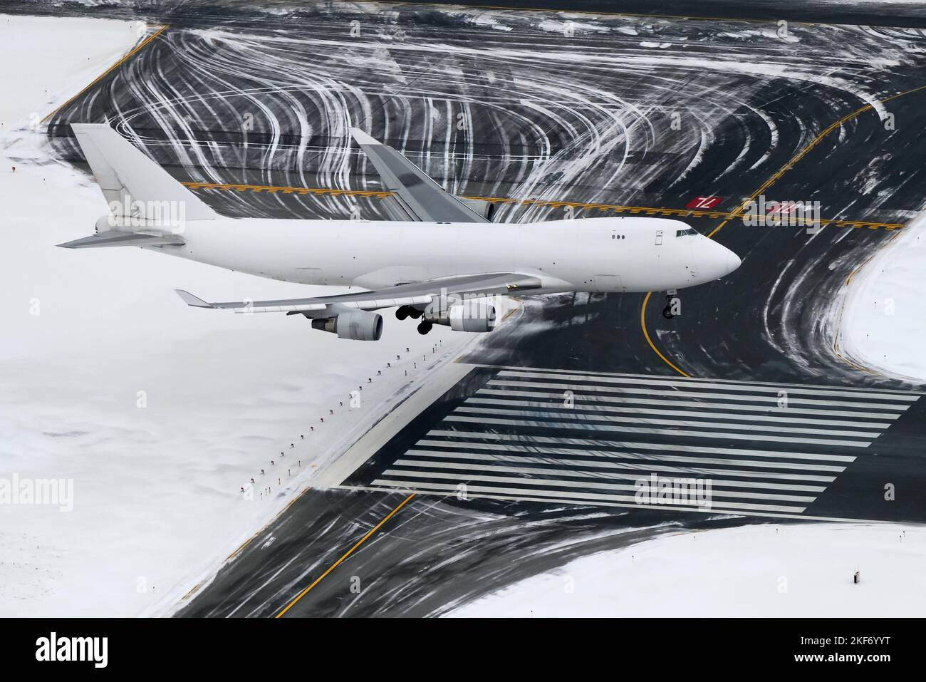 Atterrissage d'un avion blanc sur la piste de l'aéroport pendant la journée d'hiver. Gros avion non identifié pour le fret avant l'atterrissage. Quatre moteurs plane par le dessus. Banque D'Images