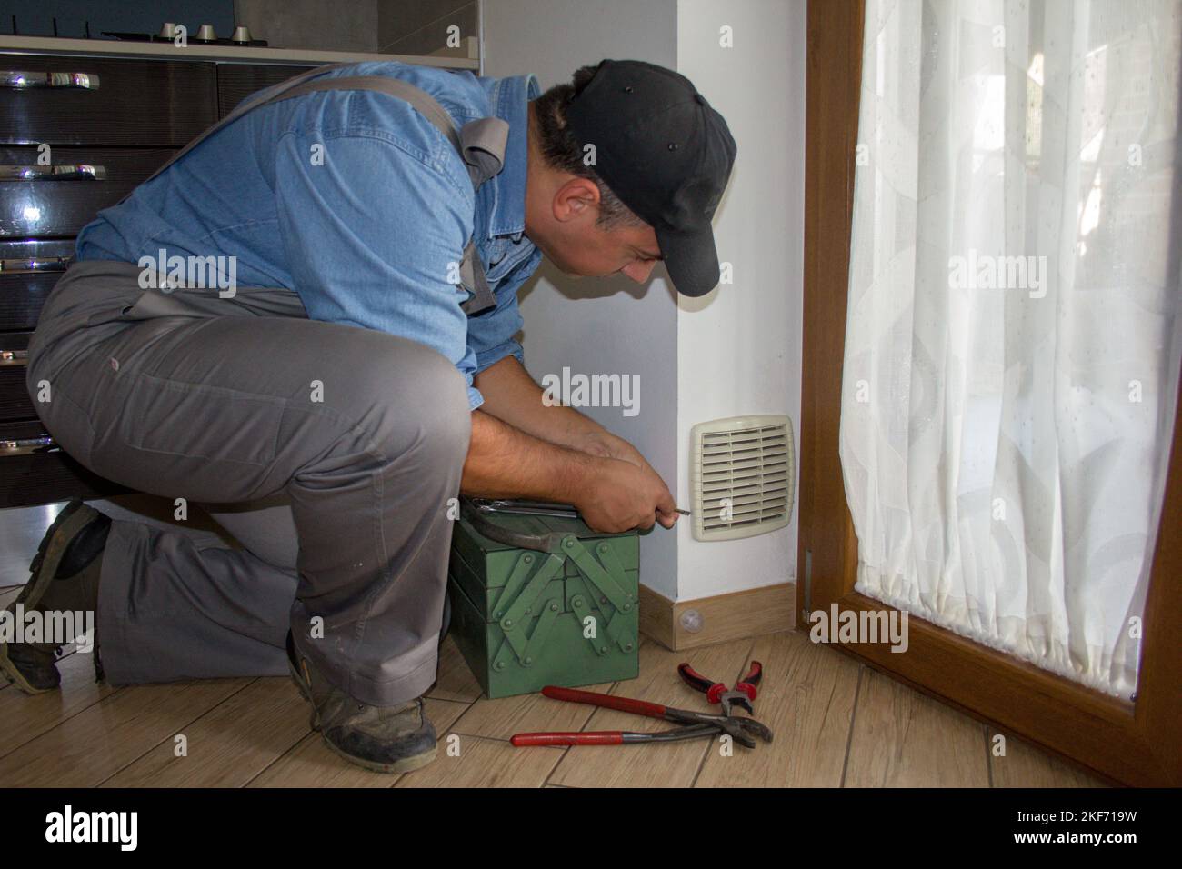 Homme de main dans la cuisine d'une maison tout en nettoyant le filtre de l'aération et de l'orifice de ventilation de la cuisinière à gaz. Banque D'Images