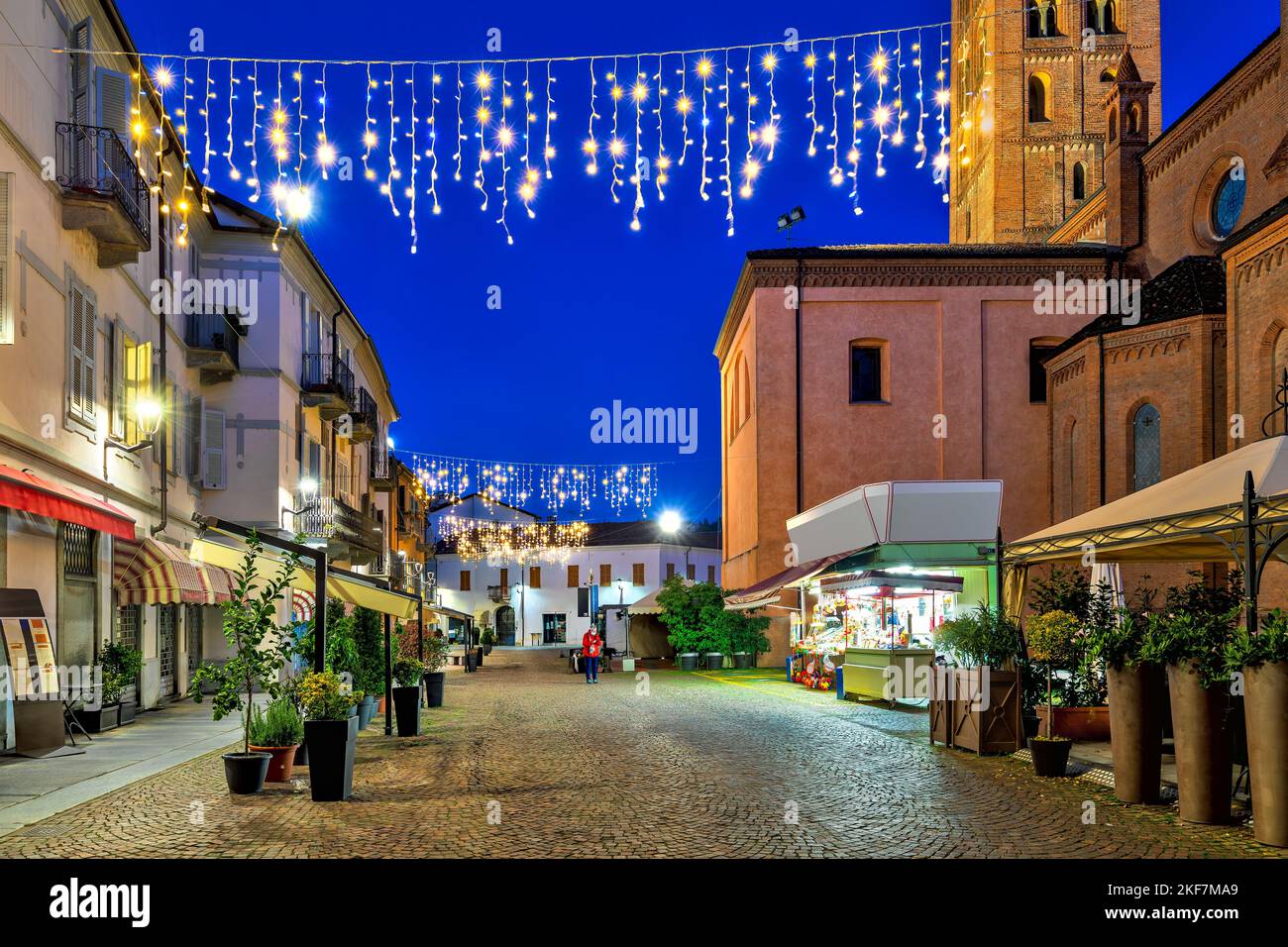 Vue sur la rue pavée de la vieille ville d'Alba illuminée de lumières de Noël dans la soirée dans le Piémont, dans le nord de l'Italie. Banque D'Images