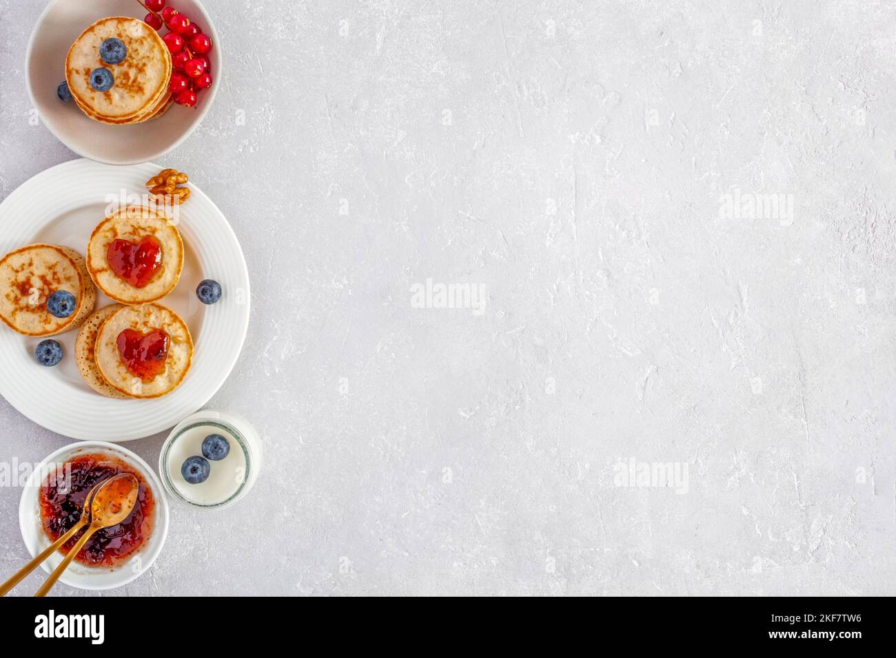 Yaourt et mini crêpes décorées de confiture en forme de coeur et de baies fraîches, idée de petit déjeuner de la Saint-Valentin, vue de dessus, espace copie Banque D'Images