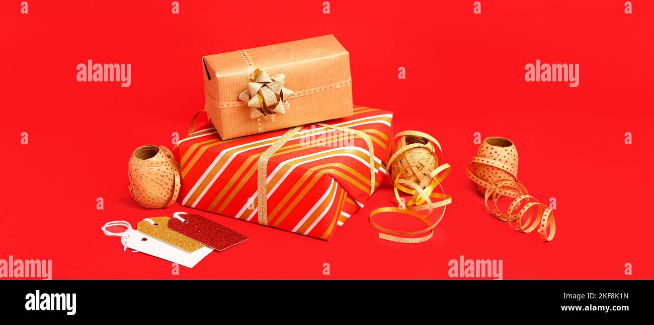 Cadeaux de Noël et matériel d'emballage sur fond rouge Banque D'Images
