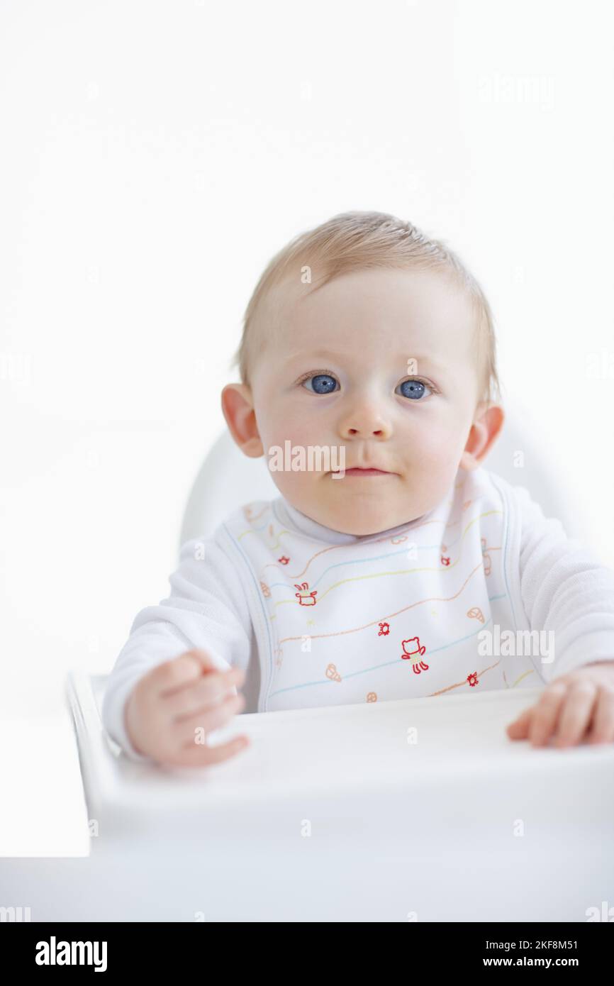 En attendant le dîner... Un adorable petit garçon assis dans sa chaise haute. Banque D'Images