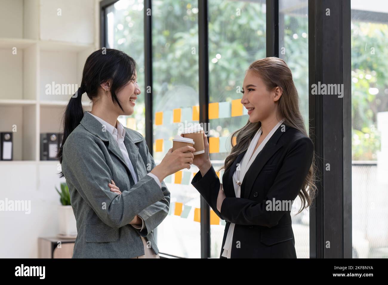 Divers employés discutant pendant la pause-café, marchant dans un bureau moderne, femme d'affaires asiatique portant des lunettes partageant des idées, discutant du projet avec Banque D'Images