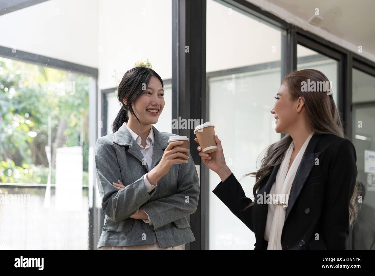 Divers employés discutant pendant la pause-café, marchant dans un bureau moderne, femme d'affaires asiatique portant des lunettes partageant des idées, discutant du projet avec Banque D'Images
