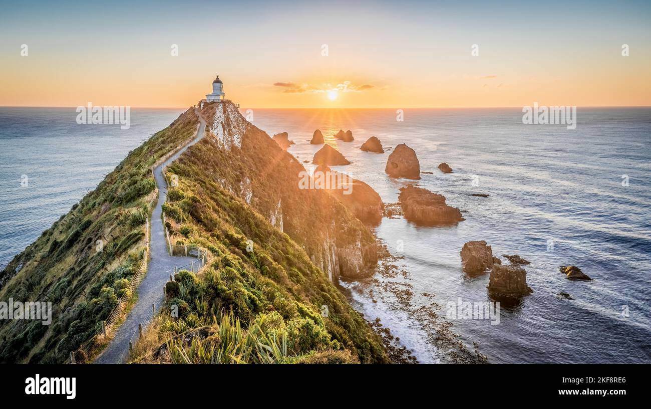 Le phare de Nugget point sur une falaise entourée par la mer pendant un beau lever de soleil en Nouvelle-Zélande Banque D'Images