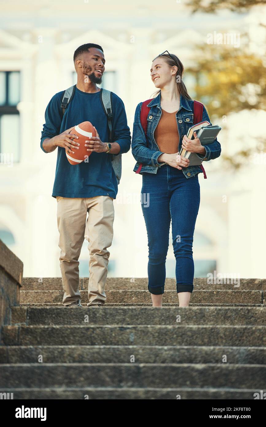 Couple, amis ou étudiants marchant dans les escaliers de l'université, de l'université ou du campus avec des livres ou ballon de football. Éducation, sport ou homme et femme avec Banque D'Images
