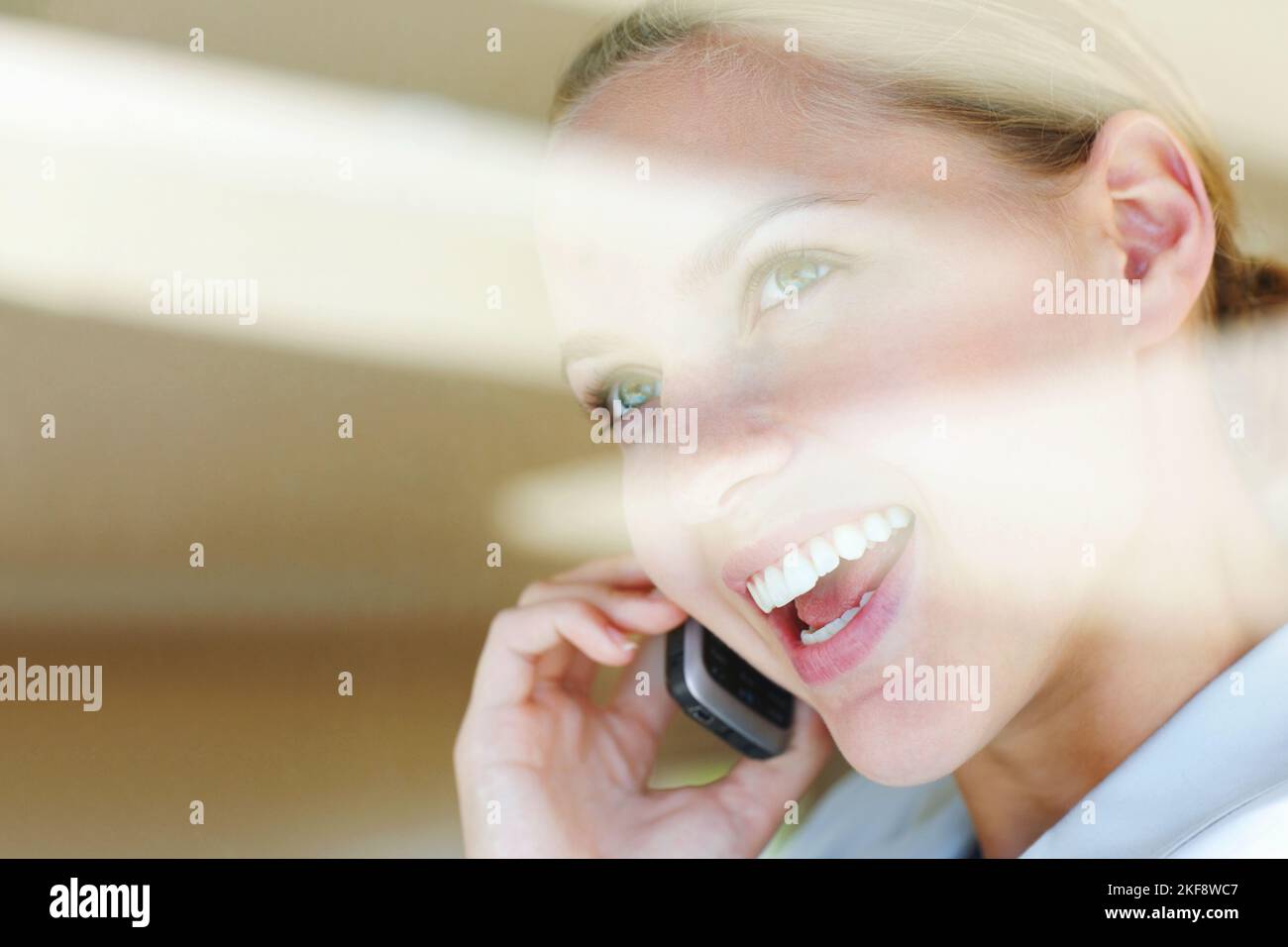 Gros plan d'une heureuse femme parlant sur le téléphone portable. Vue à travers un verre - bonne jeune femme parlant sur le téléphone portable. Banque D'Images