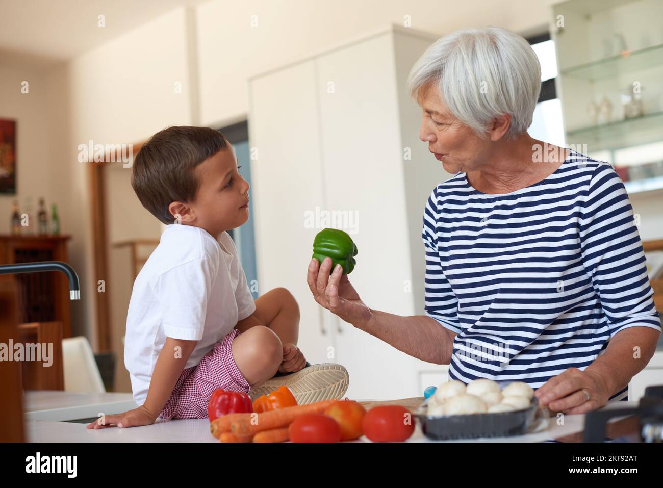 Une grand-mère prépare un dîner avec son petit-enfant dans une cuisine. Banque D'Images