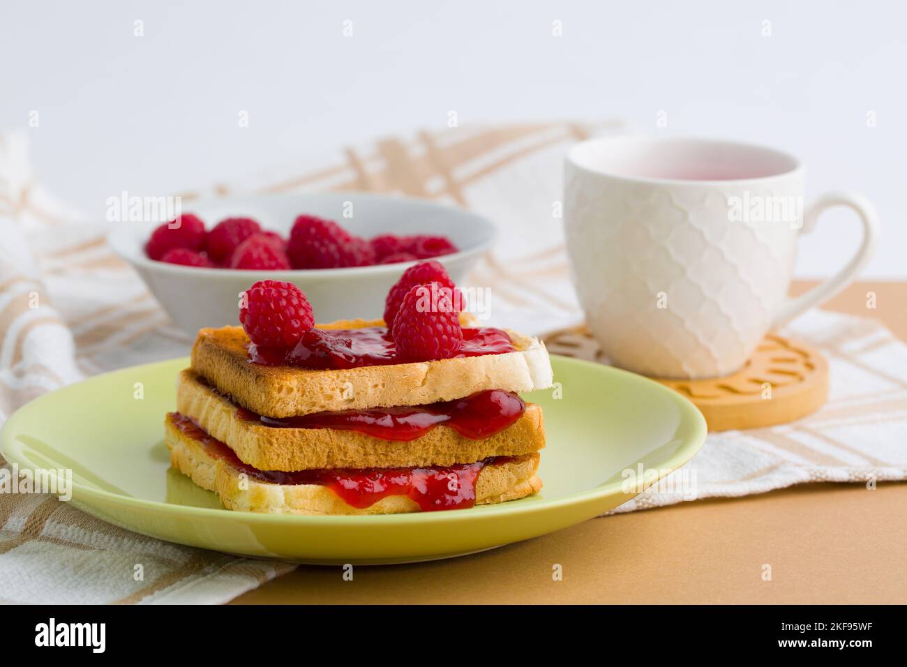 Griller avec de la confiture de framboise et une tasse de thé Banque D'Images