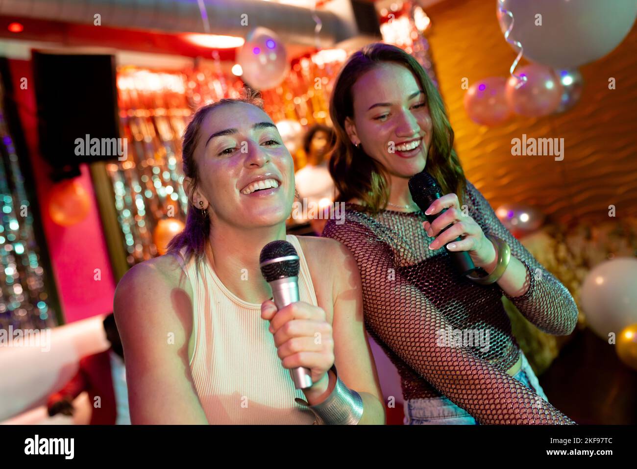 Deux amies caucasiennes qui chantent du karaoké au bar de la discothèque Banque D'Images