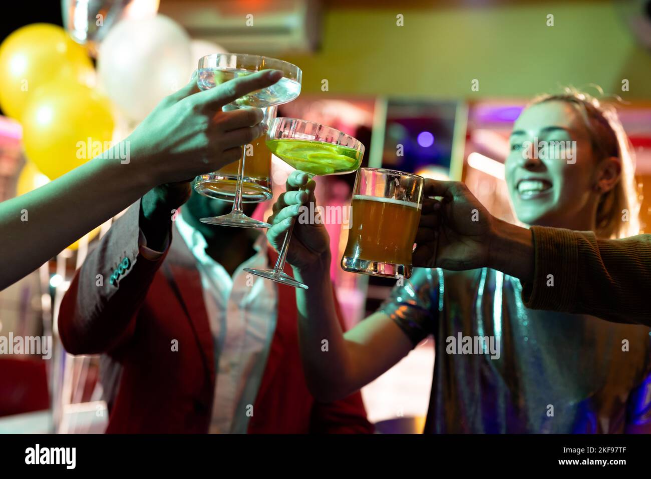 Un groupe heureux d'amis masculins et féminins qui boivent dans une discothèque Banque D'Images