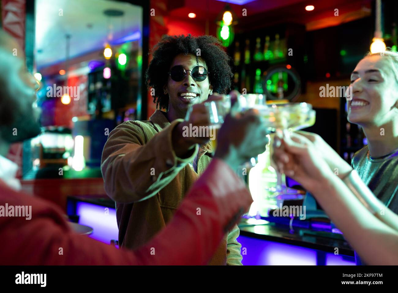 Un bon groupe d'amis hommes et femmes qui boivent au bar dans une boîte de nuit pour faire un toast Banque D'Images