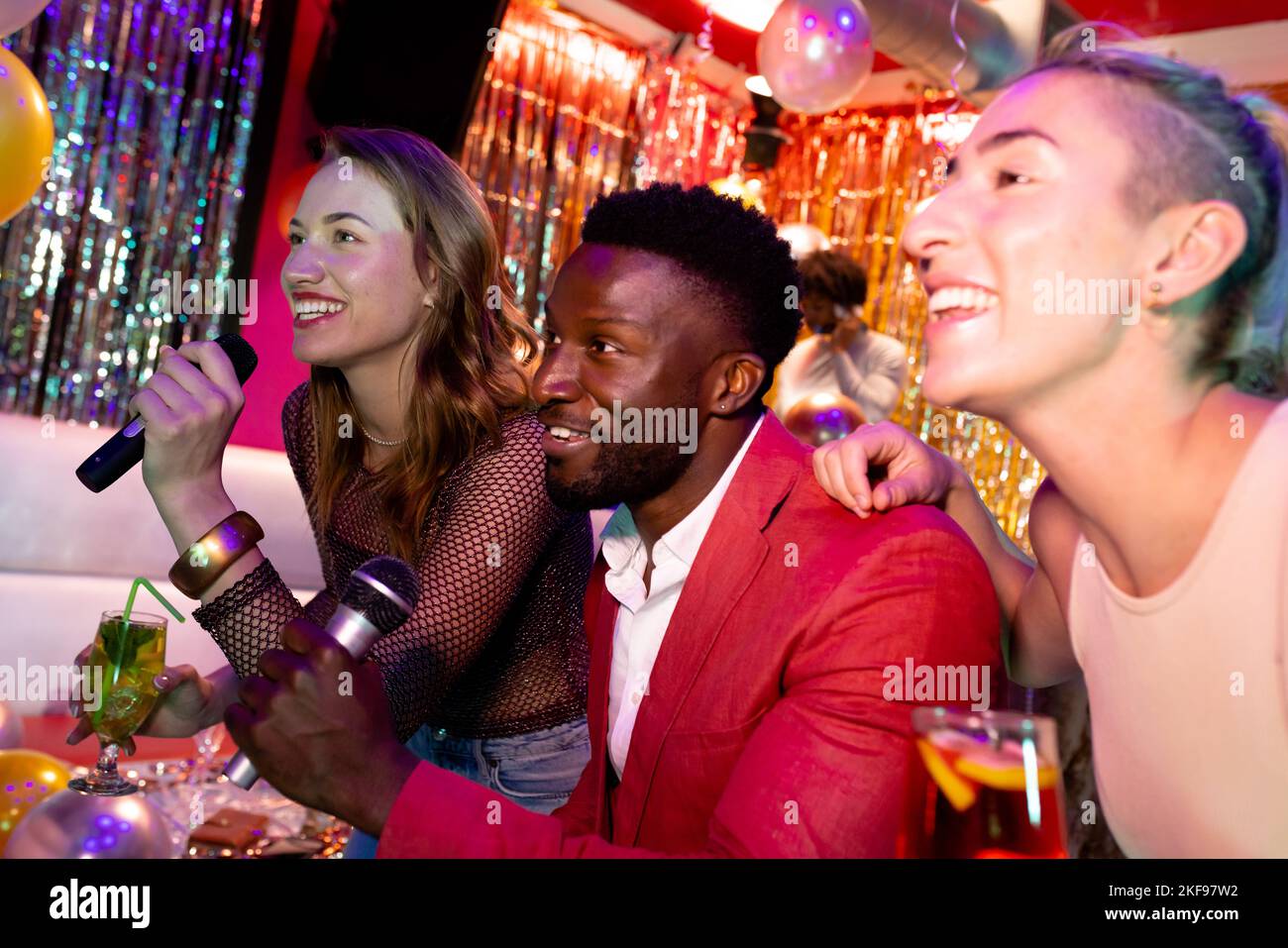 Trois amis masculins et féminins se sont amusés à chanter du karaoké et à boire dans un bar de discothèque Banque D'Images