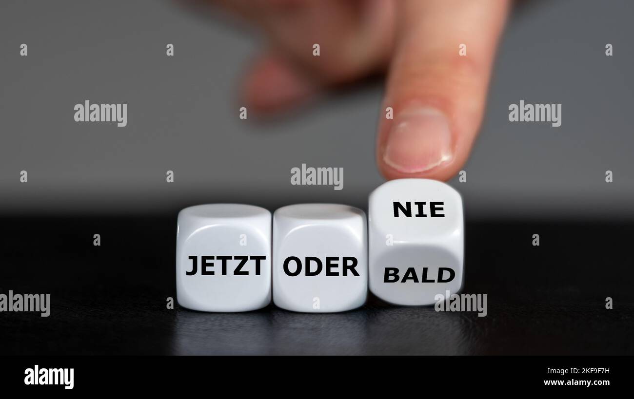 La main tourne les dés et change l'expression allemande 'jetzt oder bald' (maintenant ou bientôt) en 'jetzt oder nie' (maintenant ou jamais). Banque D'Images