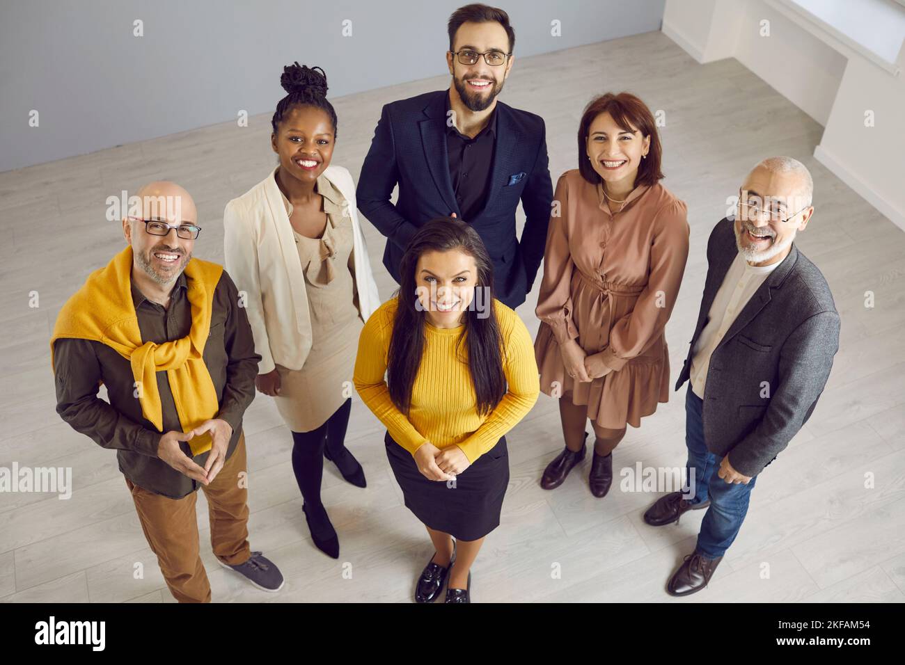 Équipe de professionnels multiraciaux heureux debout au bureau, à la recherche et souriant Banque D'Images