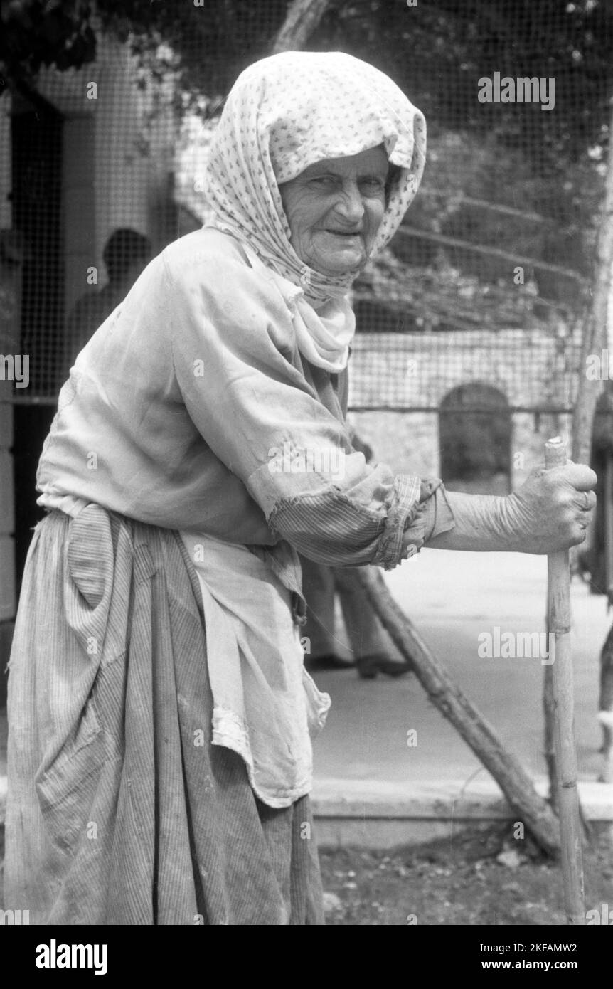 Porträt einer alten Frau mit Kopftuch, stock und Kittel in Griechenland, 1950er Jahre. Portrait d'une vieille femme avec foulard, canne et maavoir en Grèce, 1950s. Banque D'Images