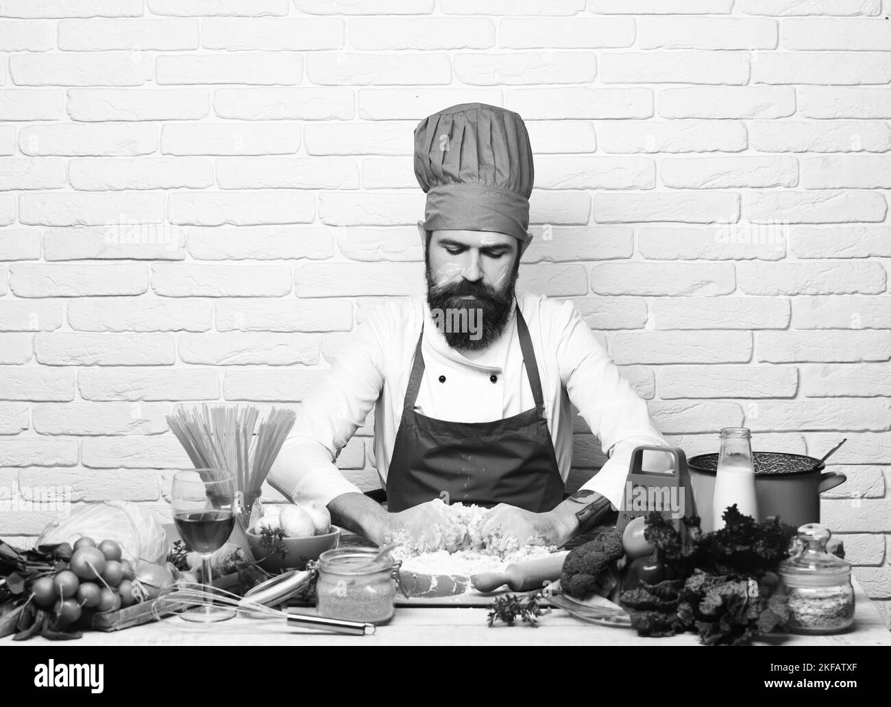 Le chef prépare de la pâte. Faire cuire avec un visage sérieux en uniforme bordeaux Banque D'Images