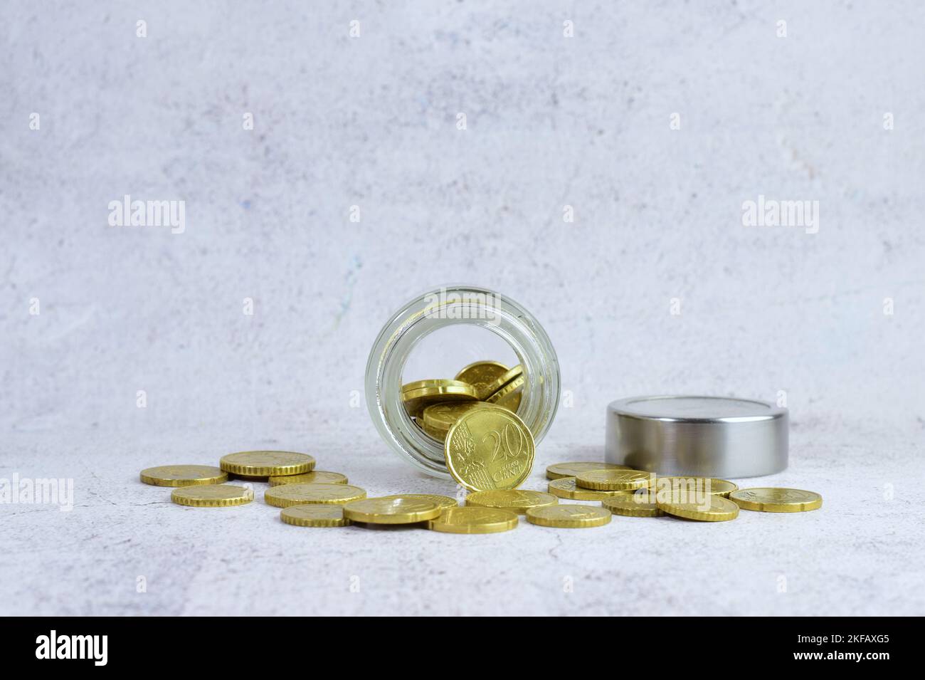 Un gros plan de centimes d'euros déversant d'un pot en verre sur un fond de mur blanc Banque D'Images