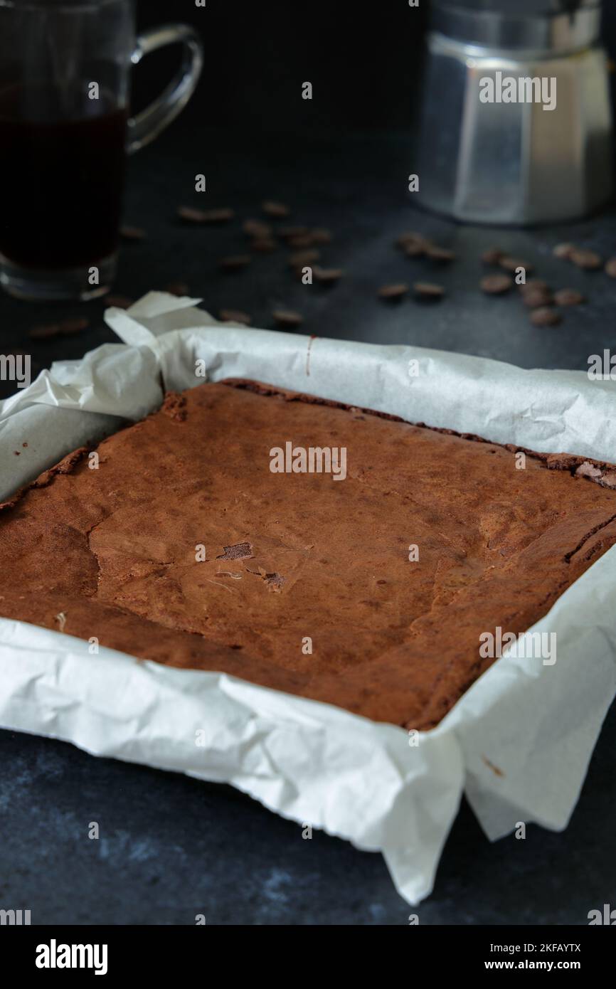 Des brownies au chocolat maison riches et indulgentes fraîches du four, toujours dans le moule avant d'être coupées en carrés avec une cafetière et une tasse Banque D'Images