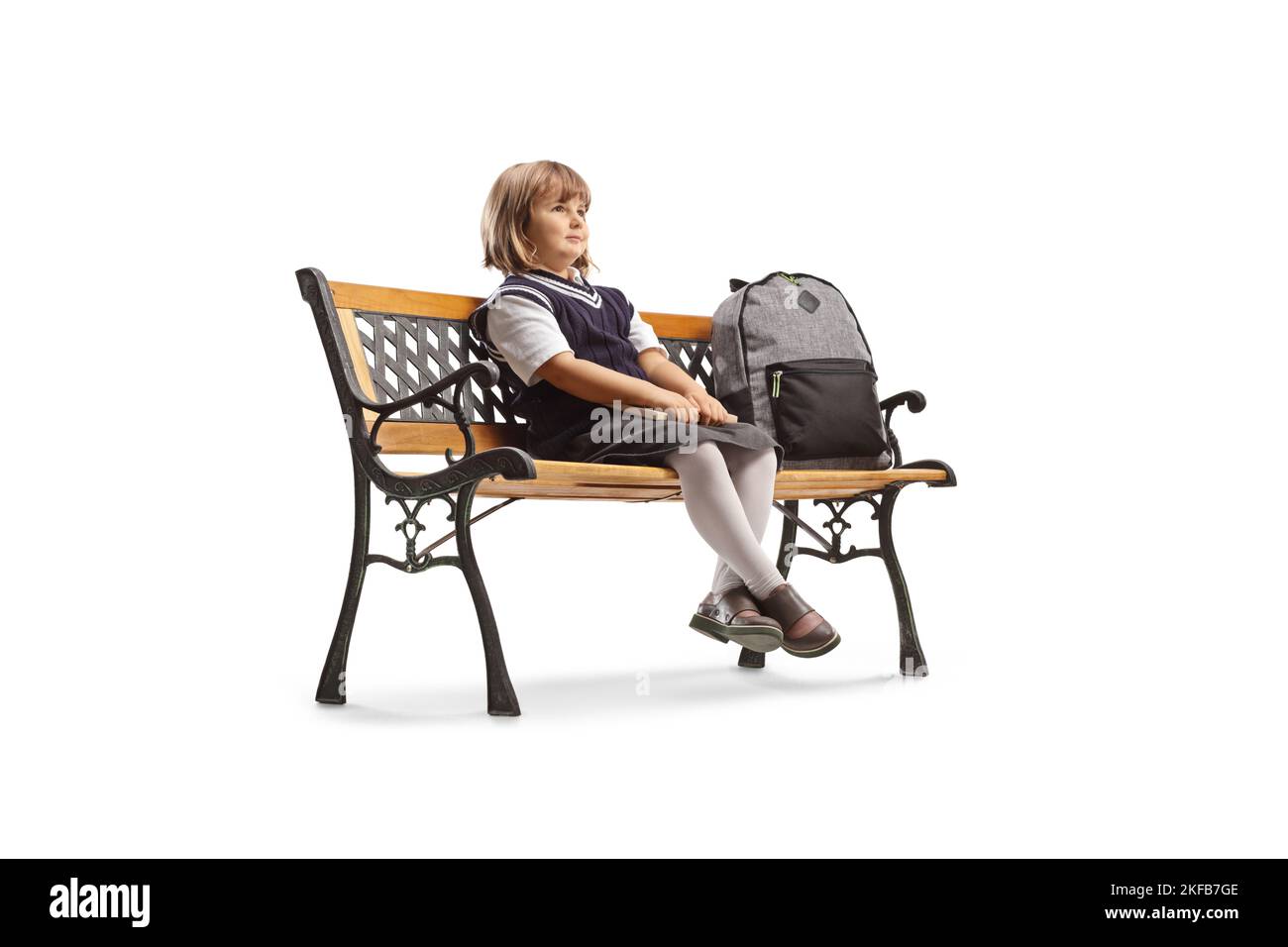 Écolière avec un sac à dos assis sur un banc et regardant loin isolée sur fond blanc Banque D'Images