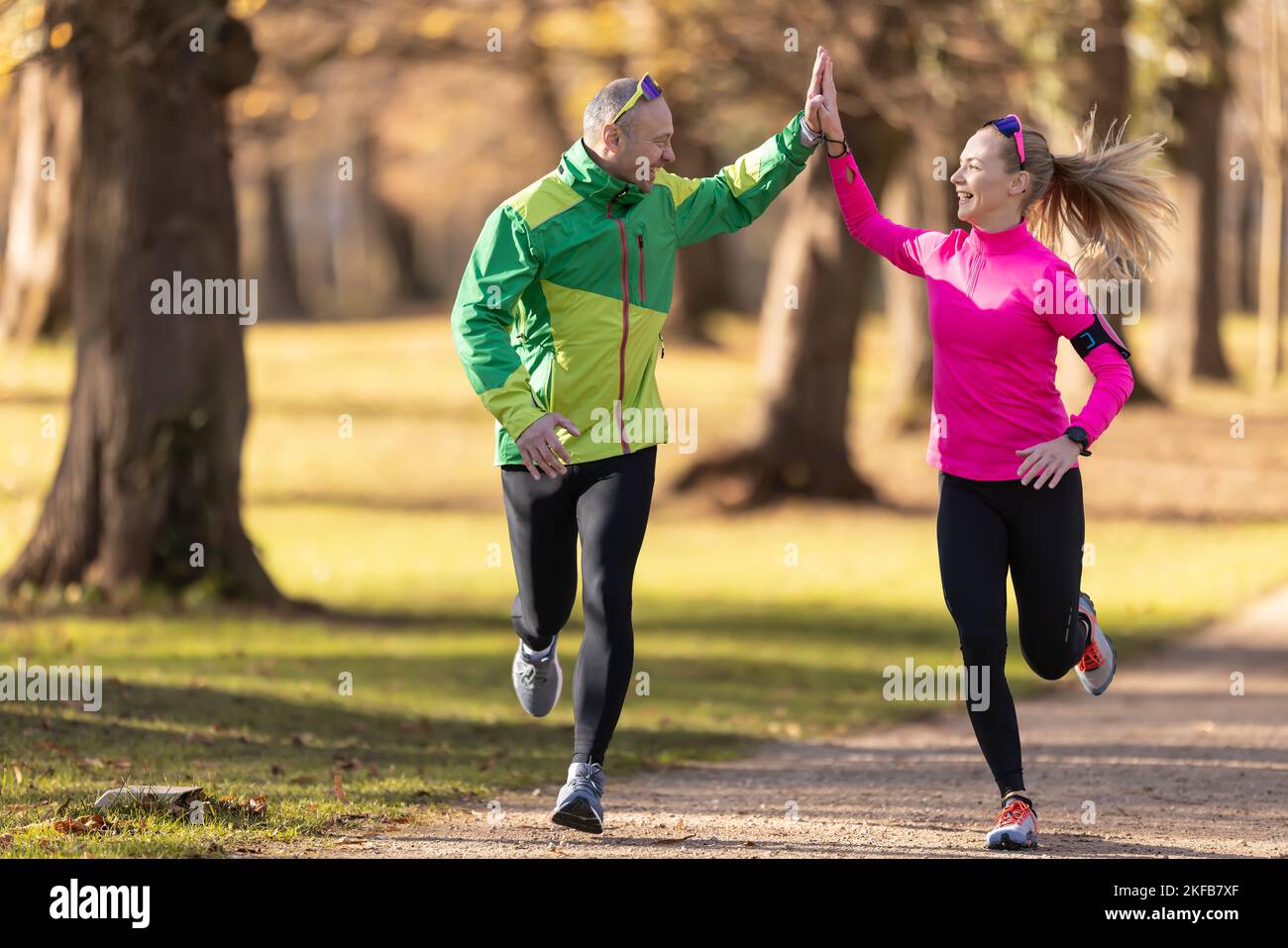 Deux coureurs adultes homme et jeune femme se soutiennent et donnent cinq hauts pendant une course. Banque D'Images