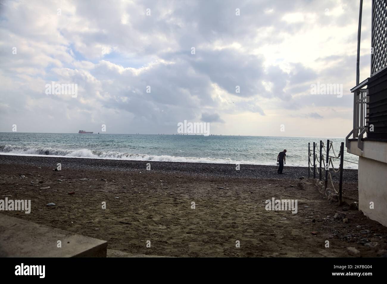 Homme sur une plage à côté d'un bâtiment par jour nuageux Banque D'Images