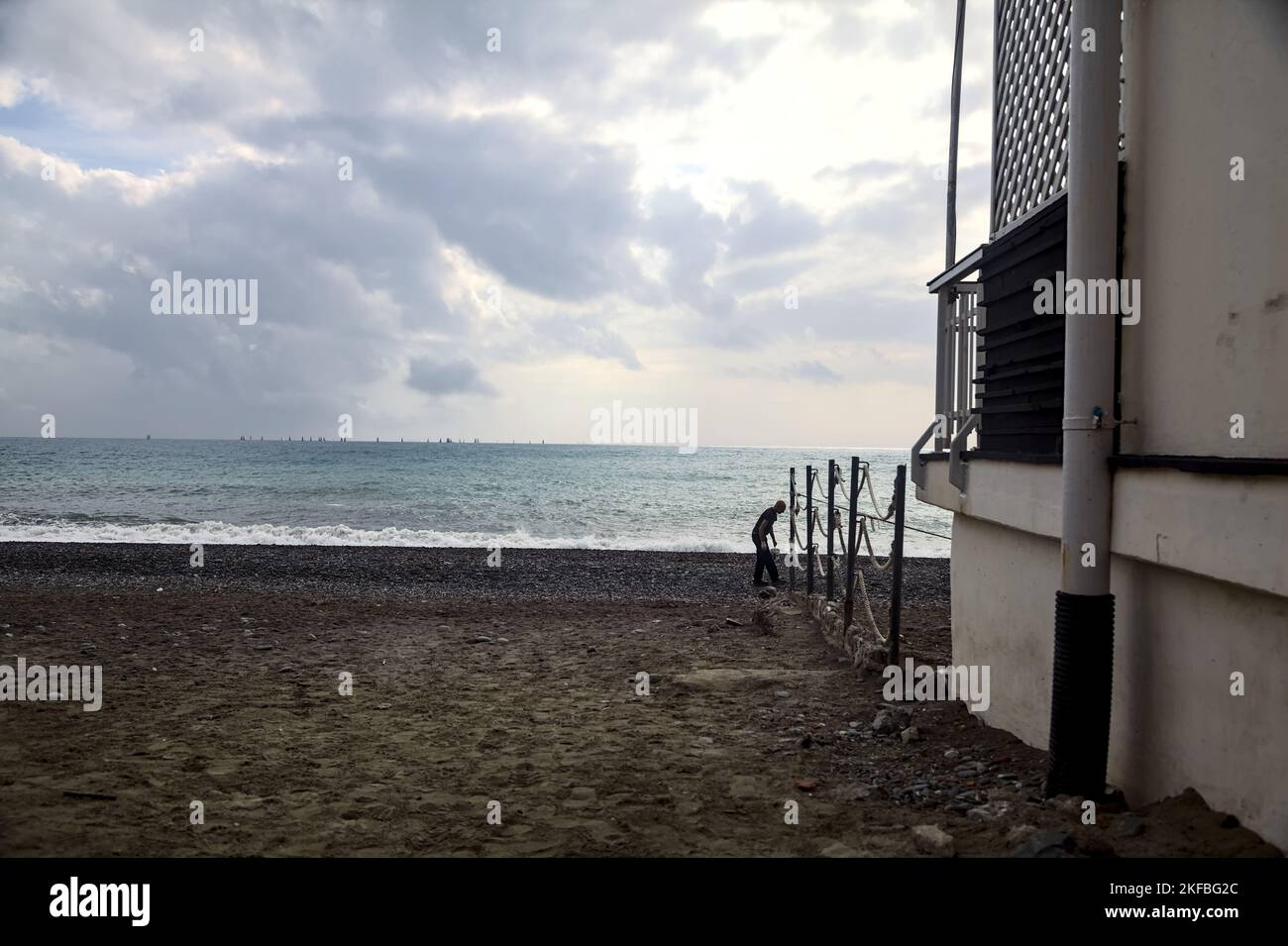 Homme sur une plage à côté d'un bâtiment par jour nuageux Banque D'Images