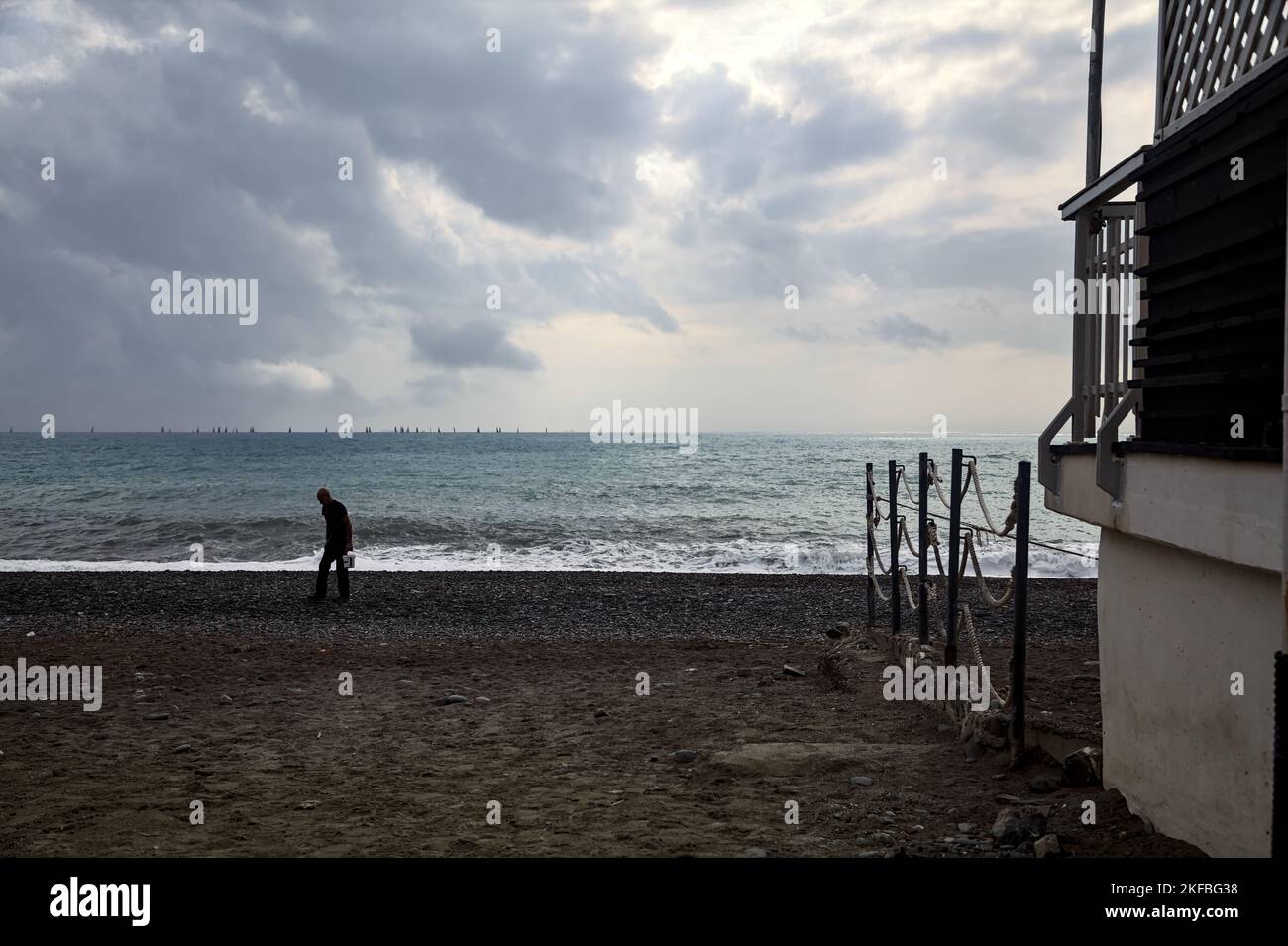 Homme sur une plage à côté d'un bâtiment par jour nuageux Banque D'Images