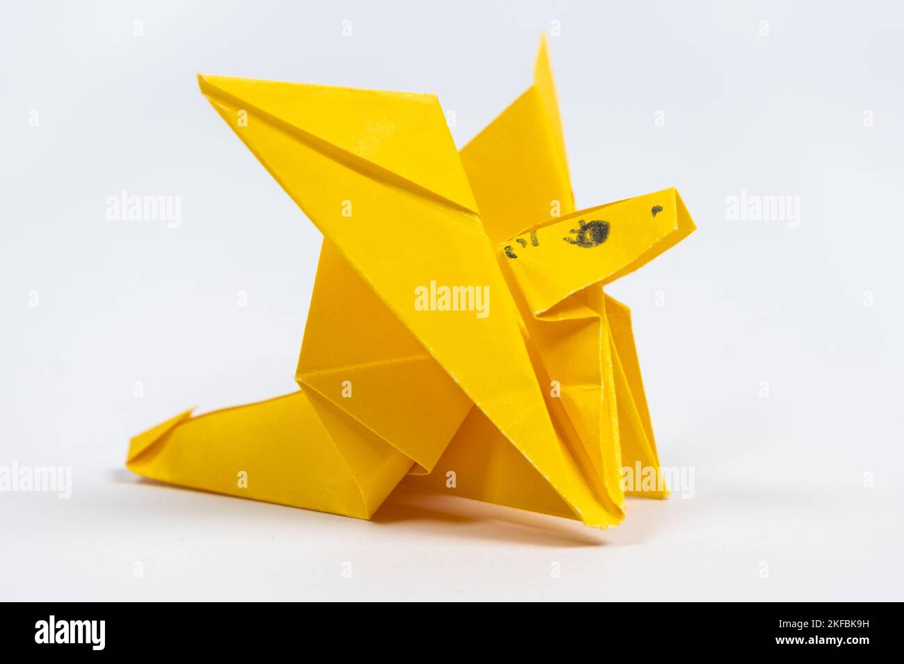 Origami jaune mignon dragon, une figurine en papier sur fond blanc Banque D'Images