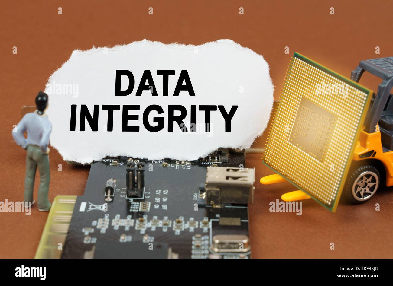 Concept informatique. Sur la carte avec des microcircuits se trouve une plaque en papier avec l'inscription - intégrité des données. À proximité se trouve un chargeur de jouets avec un processeur et Banque D'Images